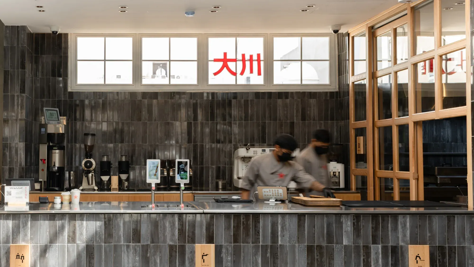 The ŌKAWA café counter, with the red 大川 sign lit in the window above a dark-tiled bar.